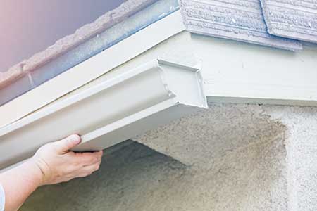 HartHaus Homes images - close up of worker's hand placing and installing new white, k-style gutters