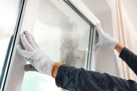HartHaus Homes iamges - close up of gloved worker hands installing a new white window